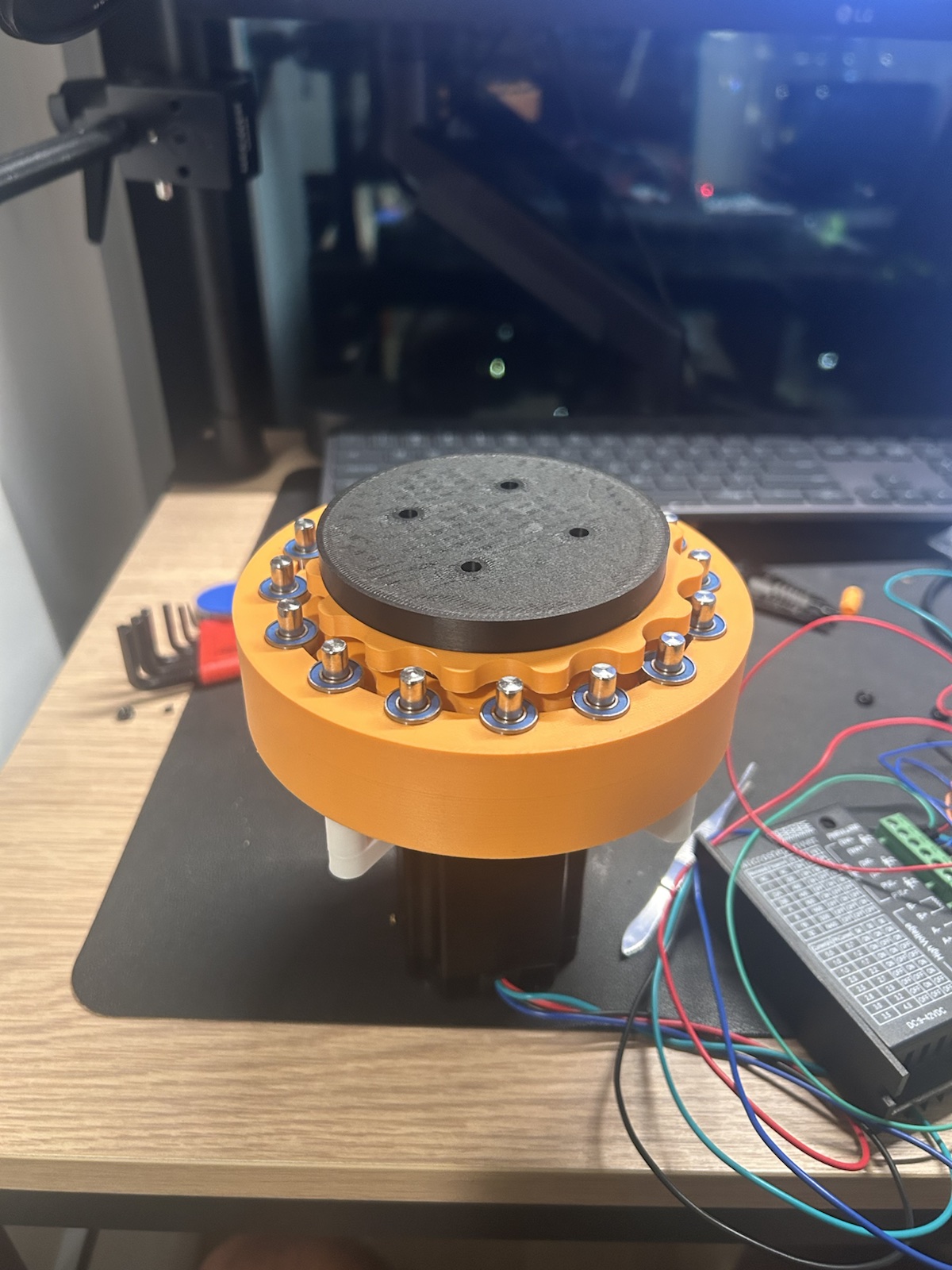 Close view of the orange cycloidal actuator prototype showing the roller pins, housing, and output plate